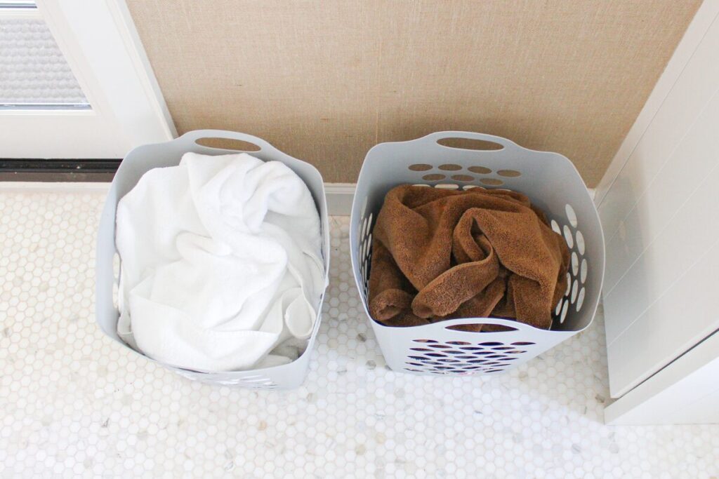 Sorting white and colored towels into separate baskets for a laundry wash.