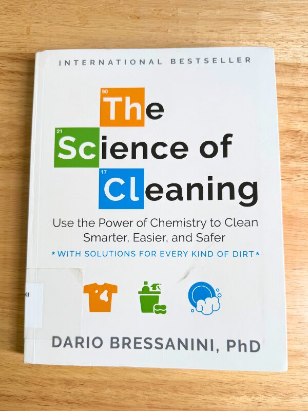 Book cover of The Science of Cleaning by Dario Bressanini resting on a light wooden table